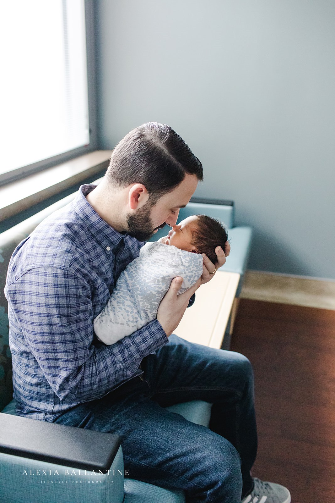 Father holding newborn baby in hospital room.