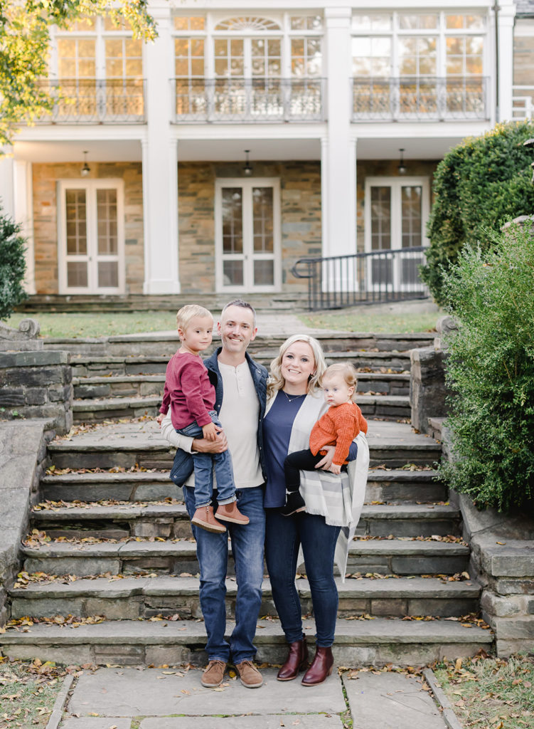 A family smiling in front of steps