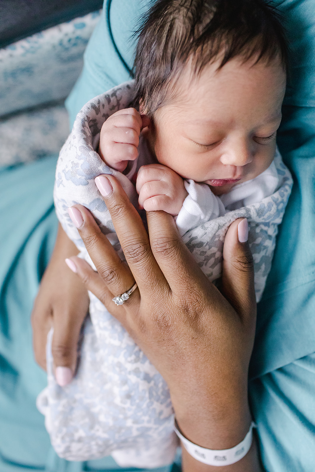 Baby with fingers wrapped around mother's finger