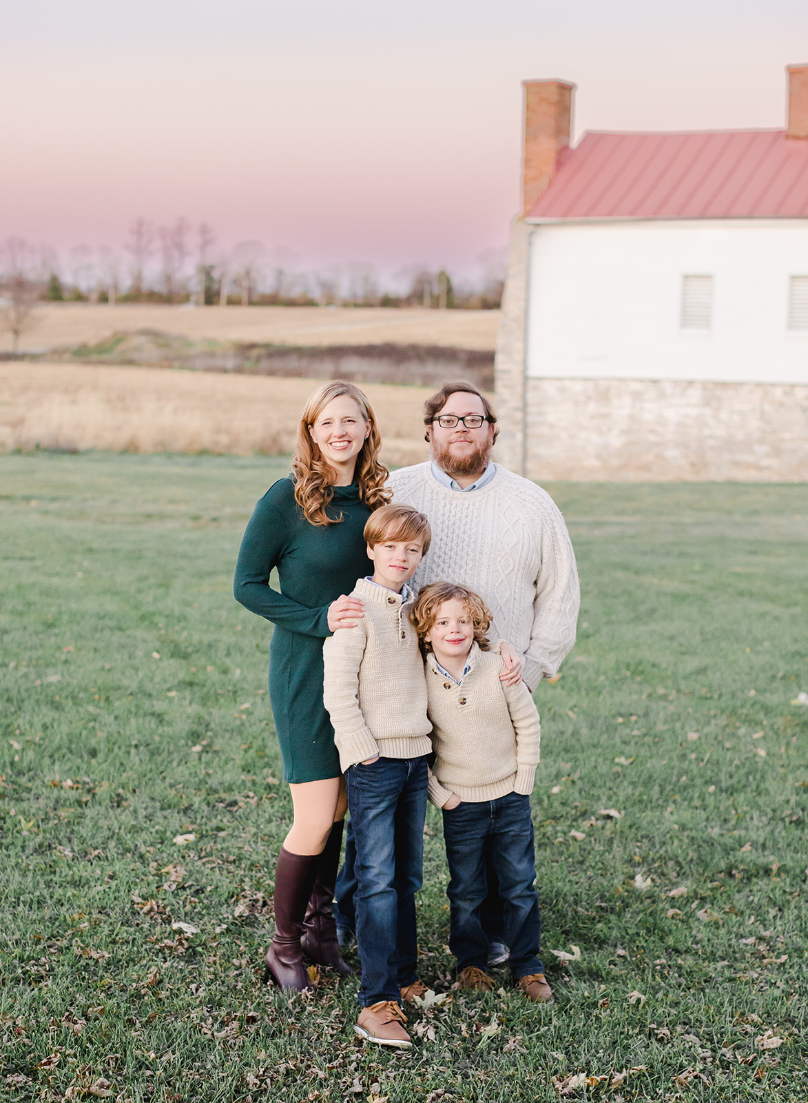 family standing in front of a barn and sunset