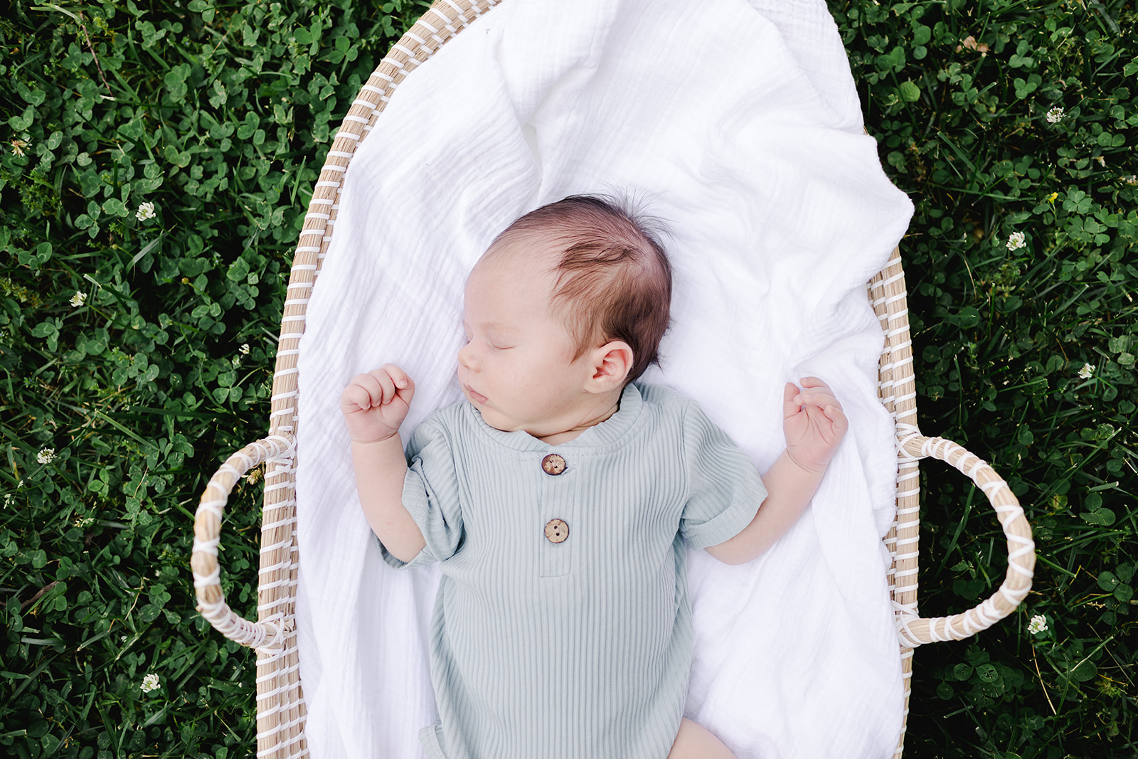 Baby boy sleeping in moses basket outside