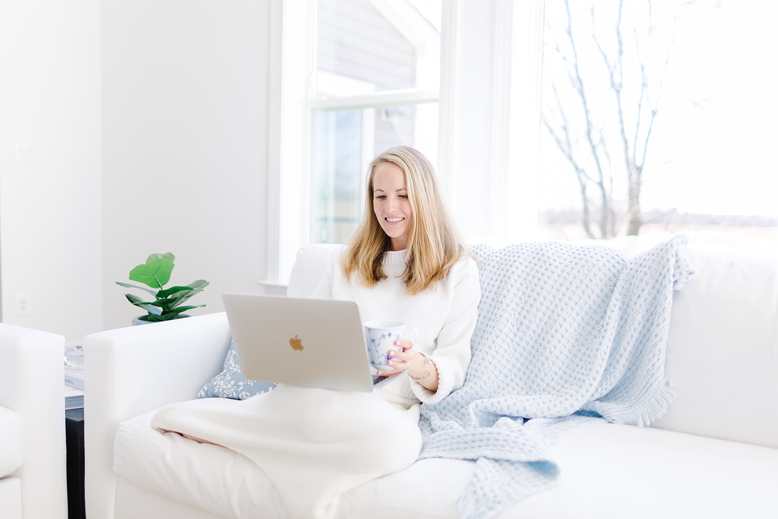woman typing on the computer while sitting on the couch